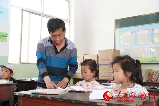 小寨村刘沟教学点刘国正老师正在为孩子们指导功课 范兴乐/摄