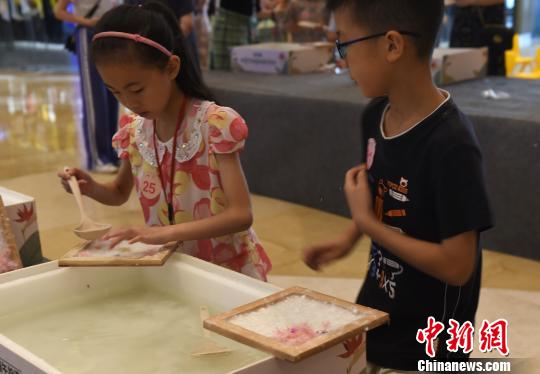 图为小朋友正在制作花草纸。 周毅 摄
