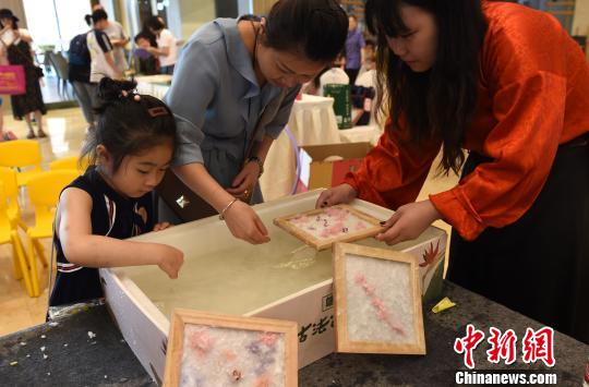 图为小朋友和家长一起学习制作古法花草纸。 周毅 摄
